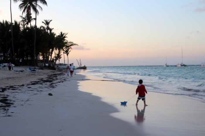 A young boy pulls his toy boat along the beach at sunset. Photo: A Bergamin.